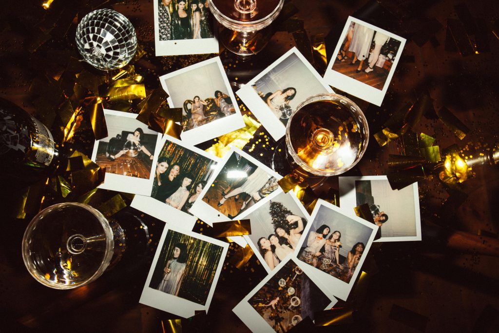 A collection of polaroid photos and glasses on a festive table, capturing party memories.